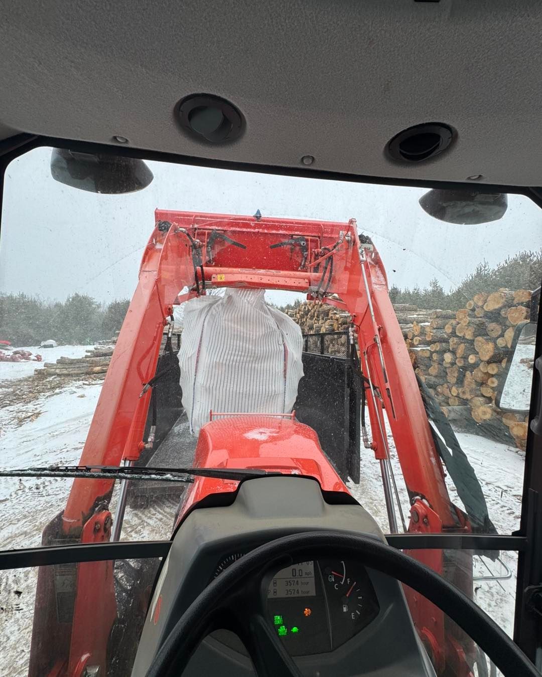 A red tractor is driving down a snowy road