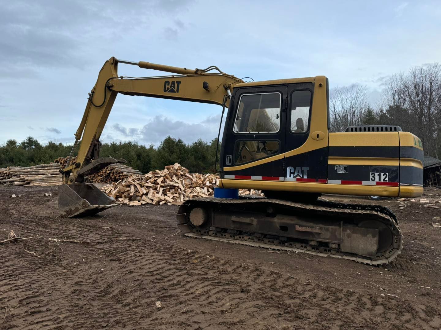 A yellow and black cat excavator is parked in a dirt field.