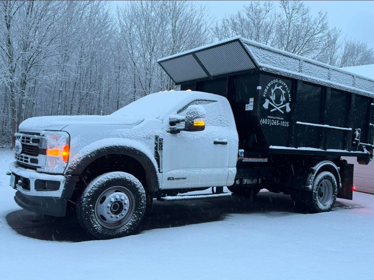 A white dump truck is parked in the snow.