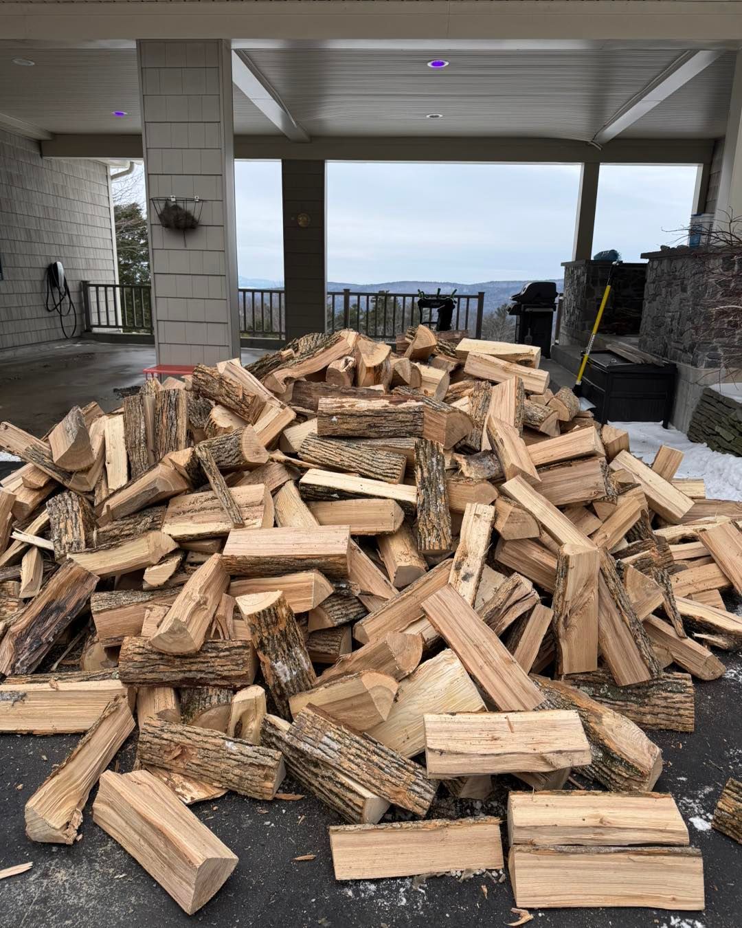 A pile of wood is sitting on the ground in front of a house.