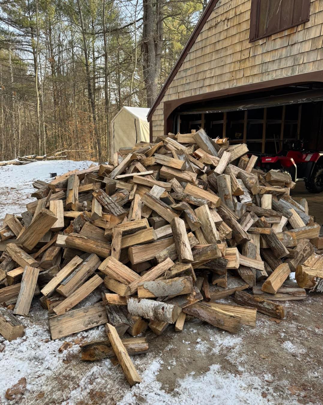 A pile of wood is sitting in front of a garage.