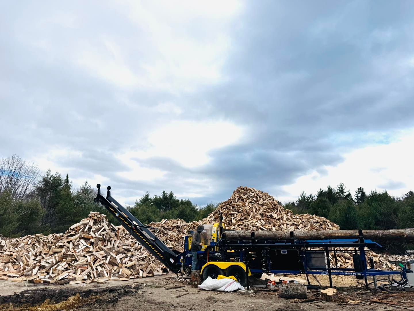 A pile of wood is being processed by a machine in a field.