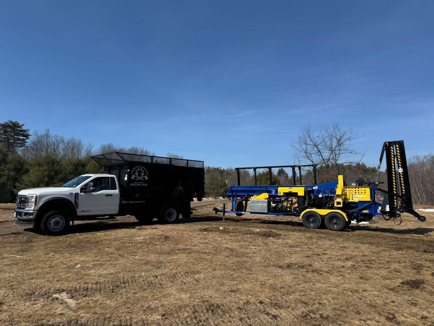 A truck with a trailer attached to it is parked in a field.