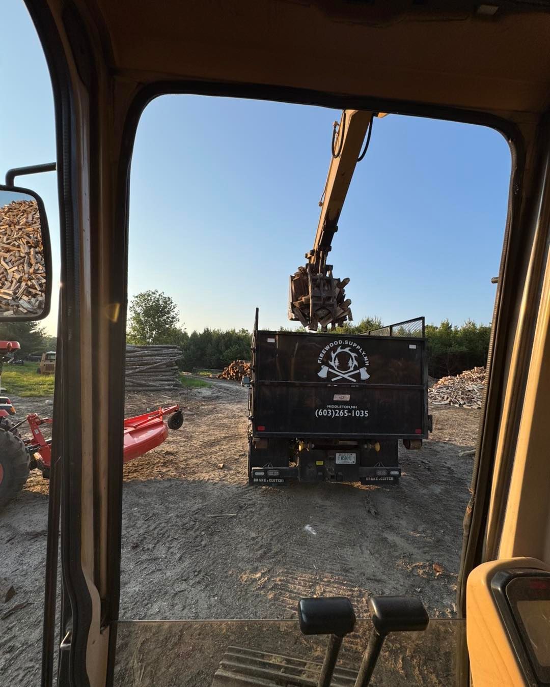 A crane is loading logs into a dump truck