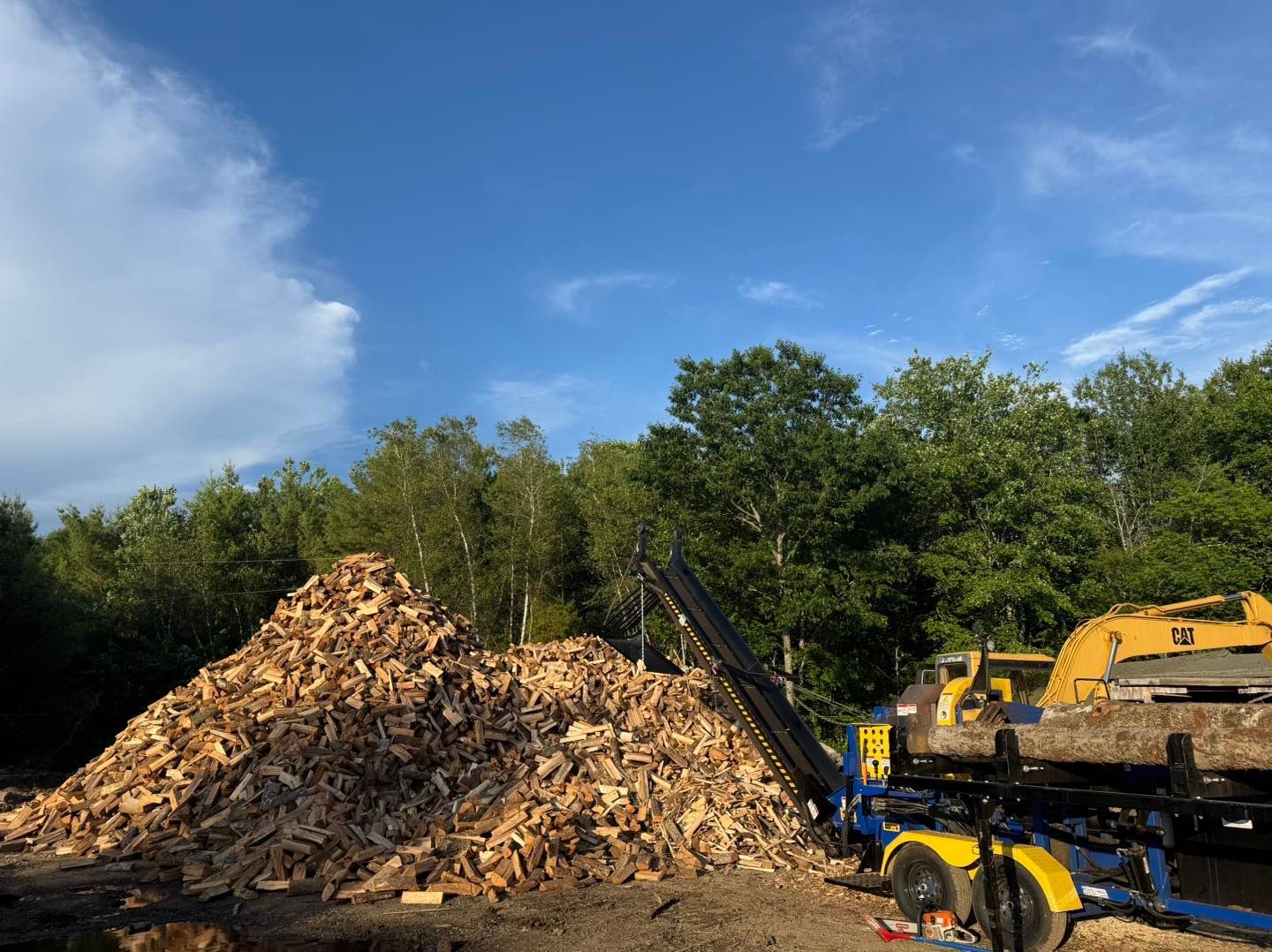 A large pile of wood is being processed by a machine.