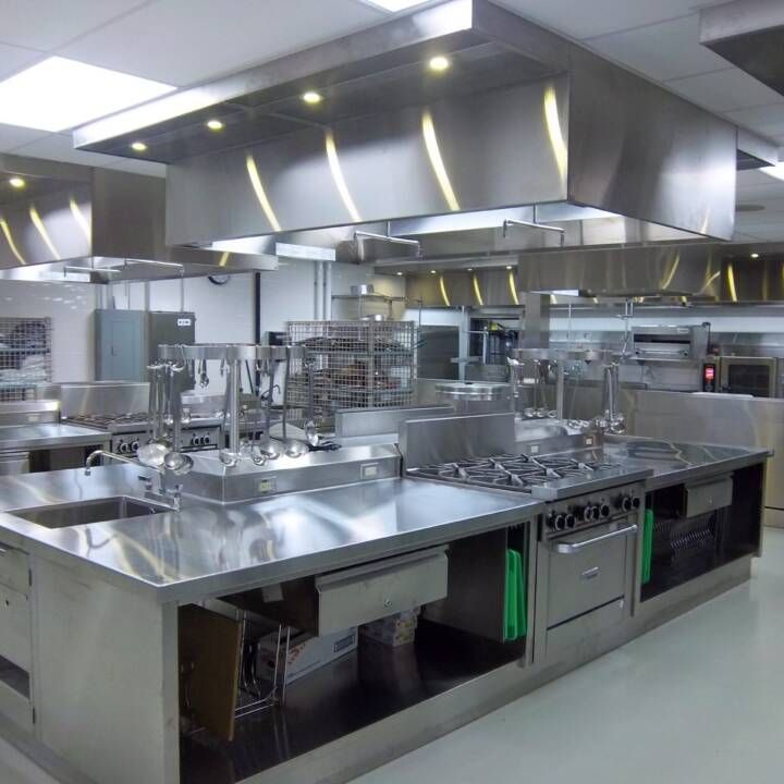 Woman in straw hat smiles, holding wine glass near a lake.