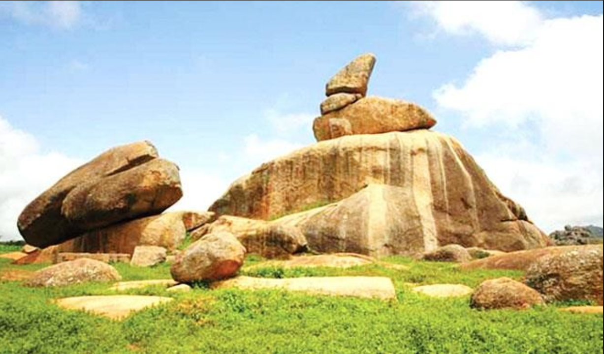 A natural rock formation features a large, stacked boulder perched atop a hill in Riyom plateau state 