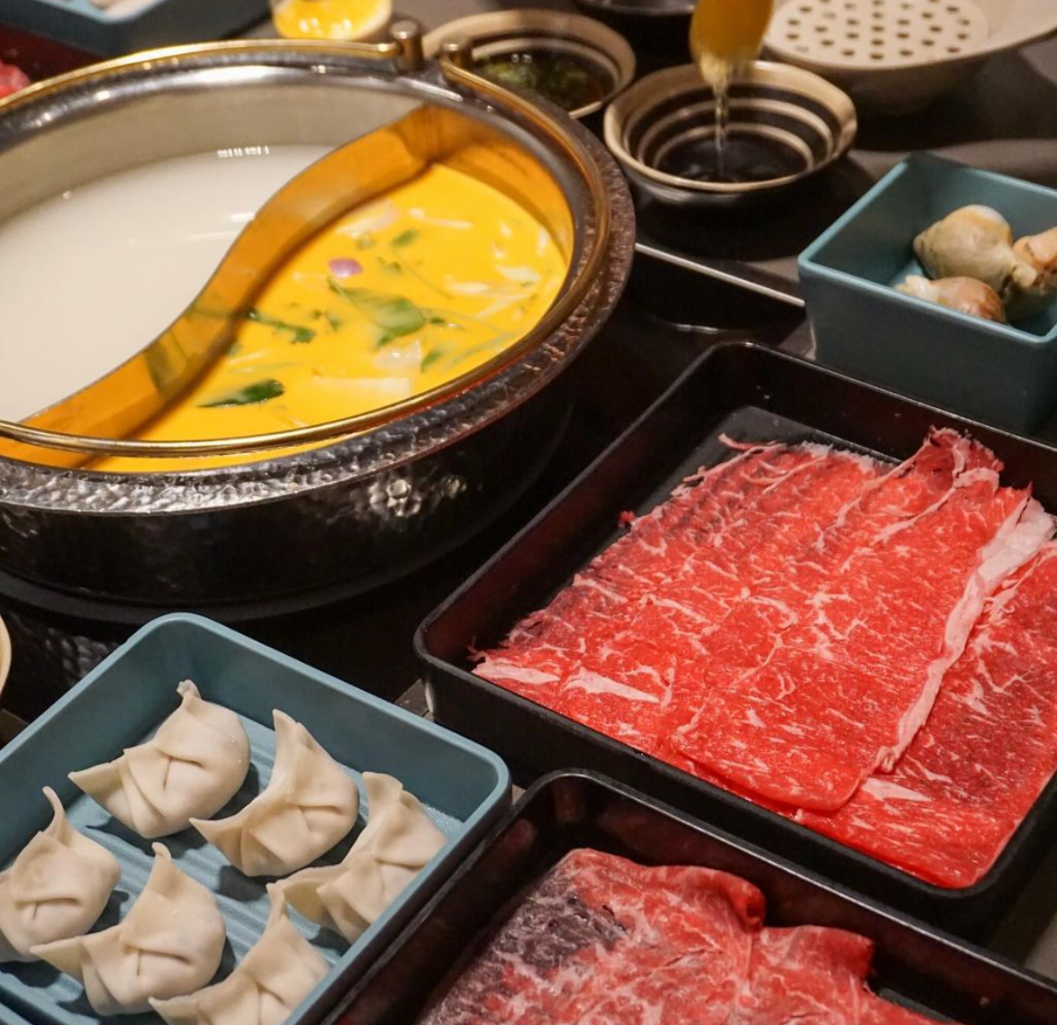A table topped with plates of meat and dumplings