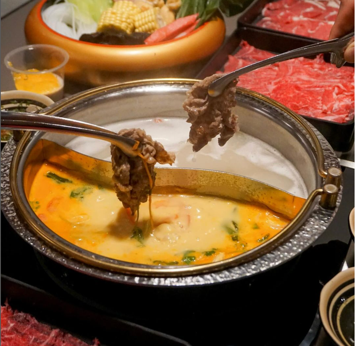 A person is taking a piece of meat out of a pot of soup