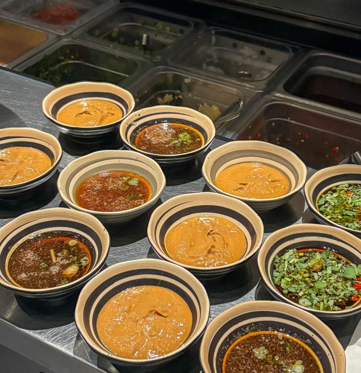A bunch of bowls filled with different types of soup on a table.