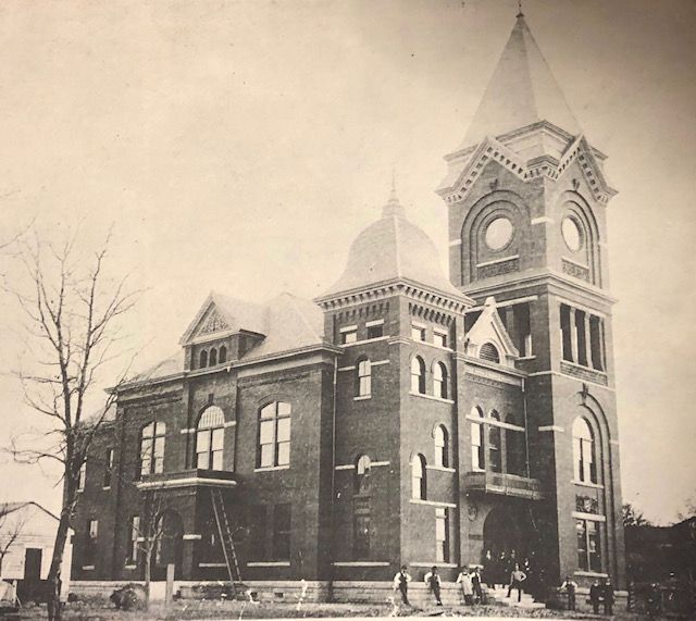 a black and white photo of a large brick building with a clock tower