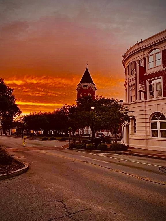 a sunset over a city street with a clock tower in the background .