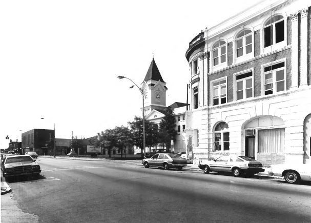 a black and white photo of a street with a clock tower in the background