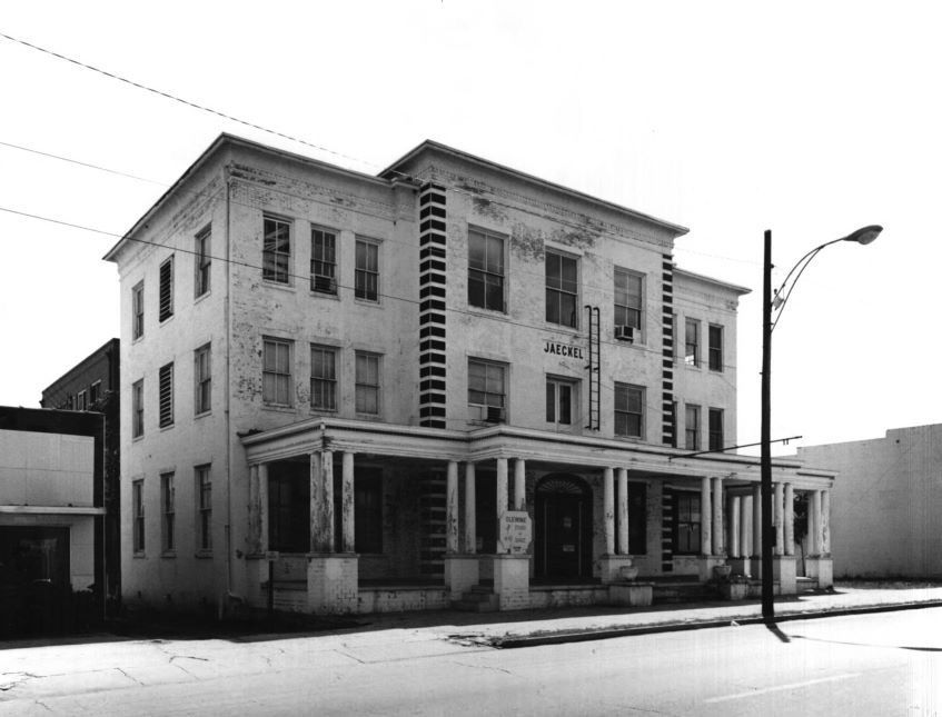 a black and white photo of an old building with a street light in front of it