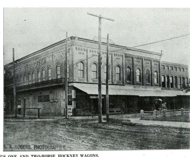a black and white photo of a building that says ' one and two horse rickney wagons ' on it