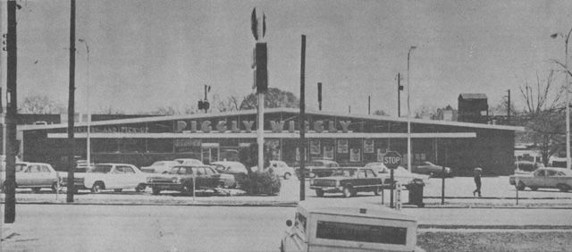 a black and white photo of a grocery store with cars parked in front of it