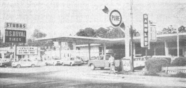 a black and white photo of a gas station with a sign that says pure