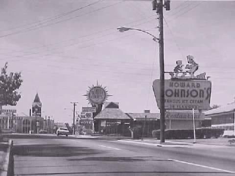 a black and white photo of a street with a sign that says howard johnson 's
