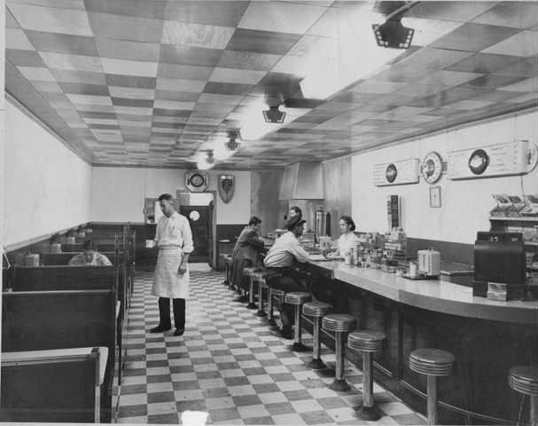 a black and white photo of a diner with people sitting at tables