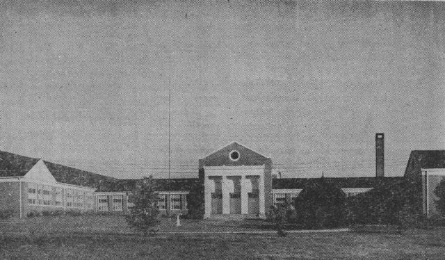 a black and white photo of a large building with a chimney in the background .