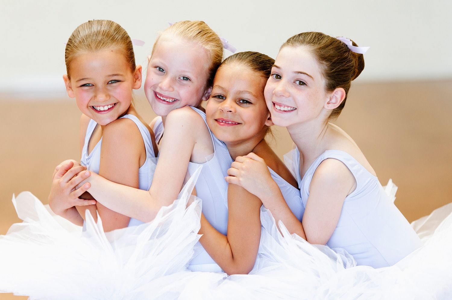 Four young girls in ballet tutus smiling.