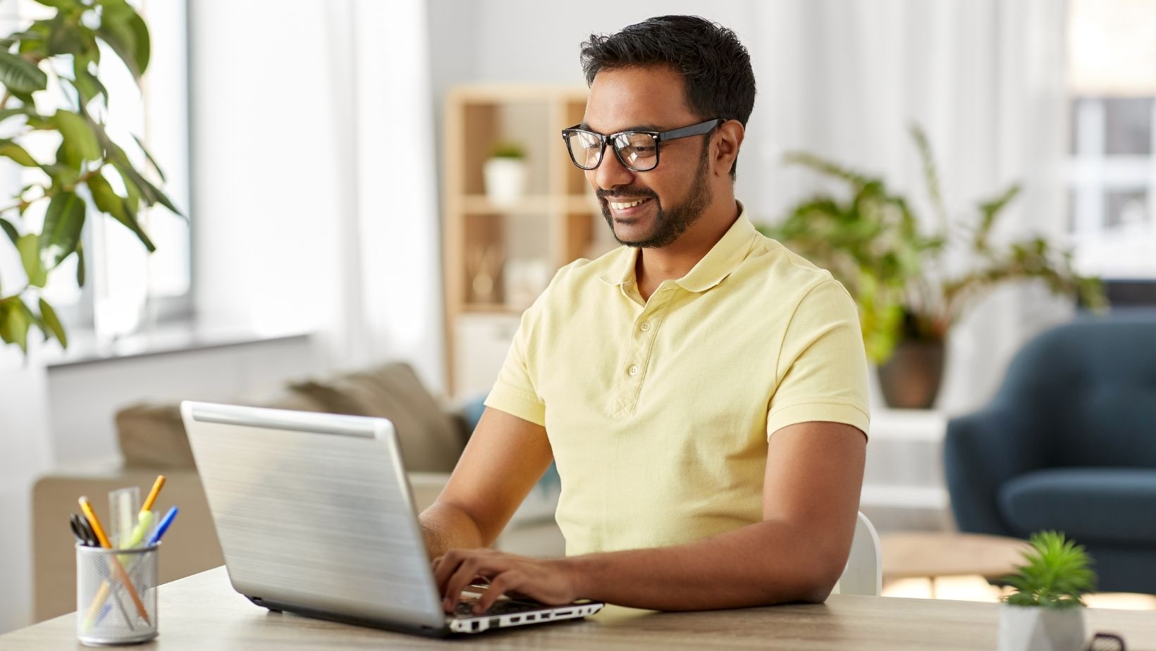 A man is sitting at a desk using a laptop computer.