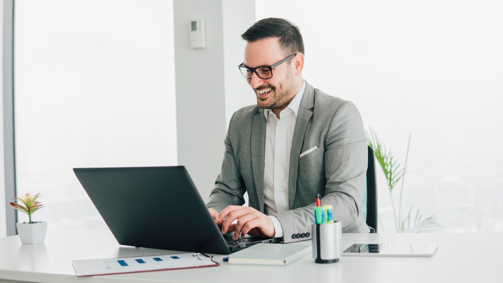 A man is sitting at a desk using a laptop computer.