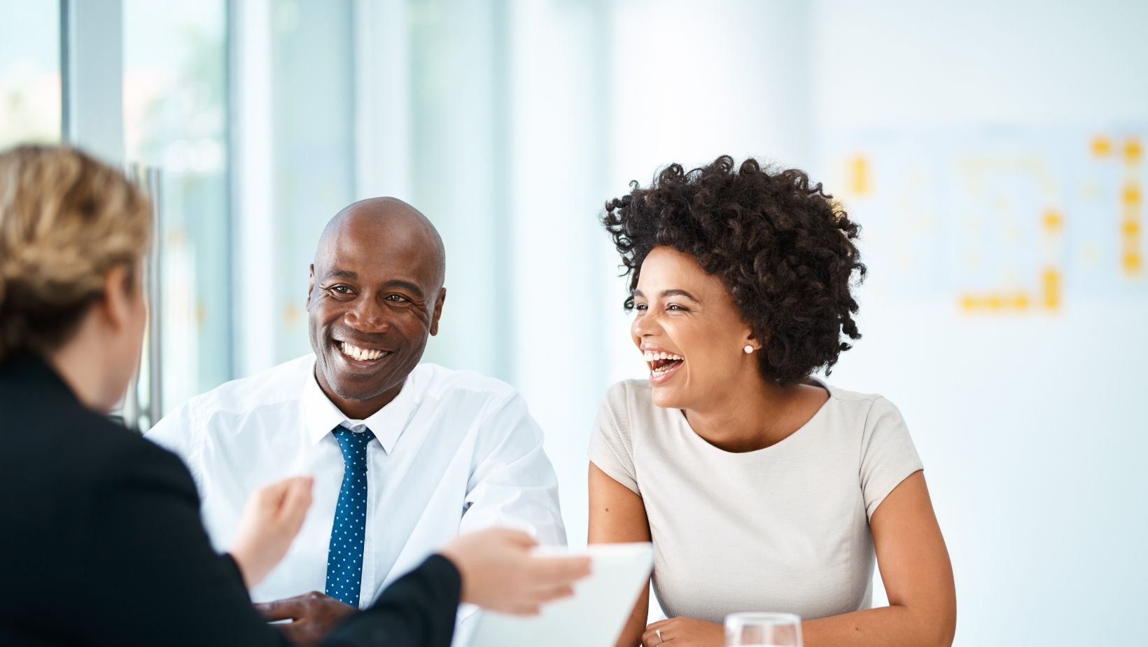 A group of people are sitting at a table having a meeting and laughing.