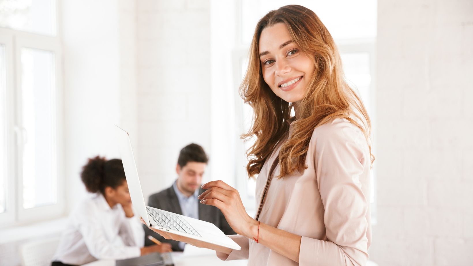 A woman is holding a laptop computer in front of a group of people.