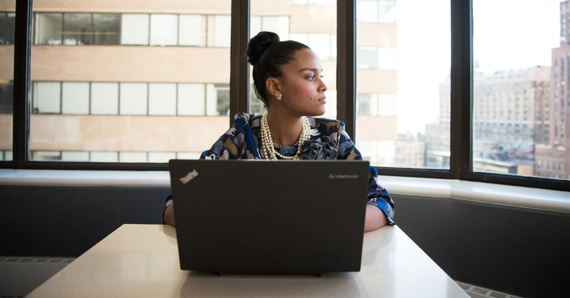 This is an image illustrating the switch from Quickbooks to NetSuite. It features a woman working on a laptop in an office.