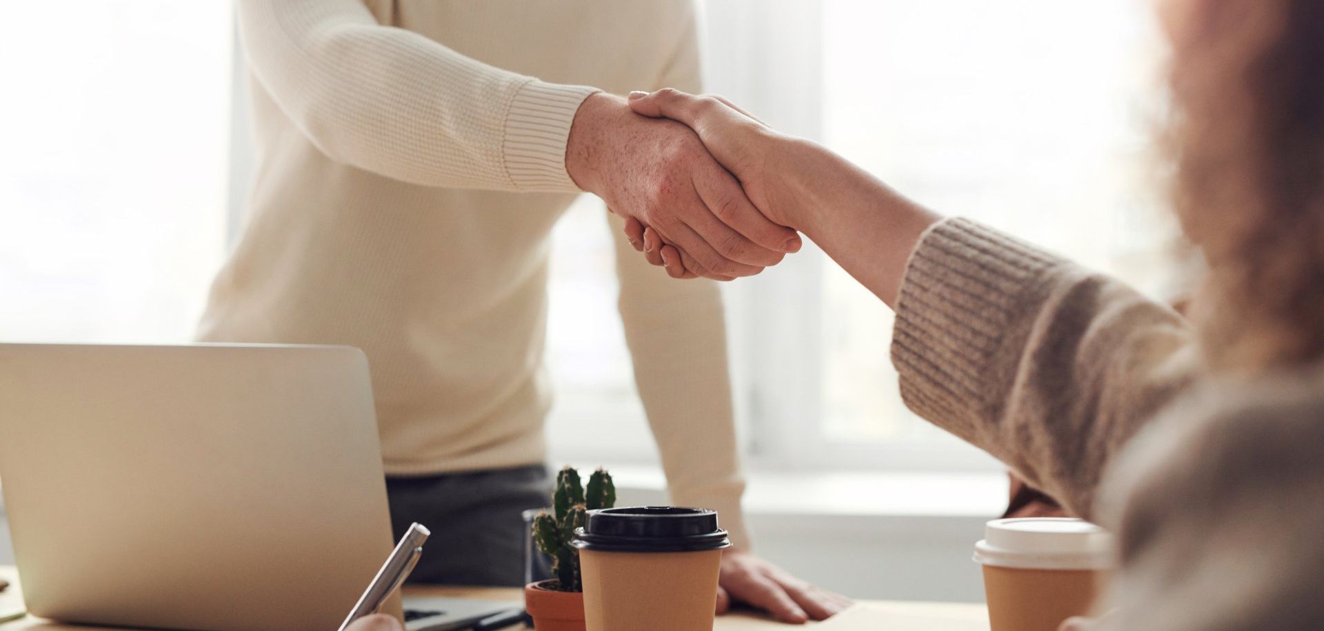 This is an image illustrating the concept of NetSuite implementation partners. It features two people shaking hands in an office.