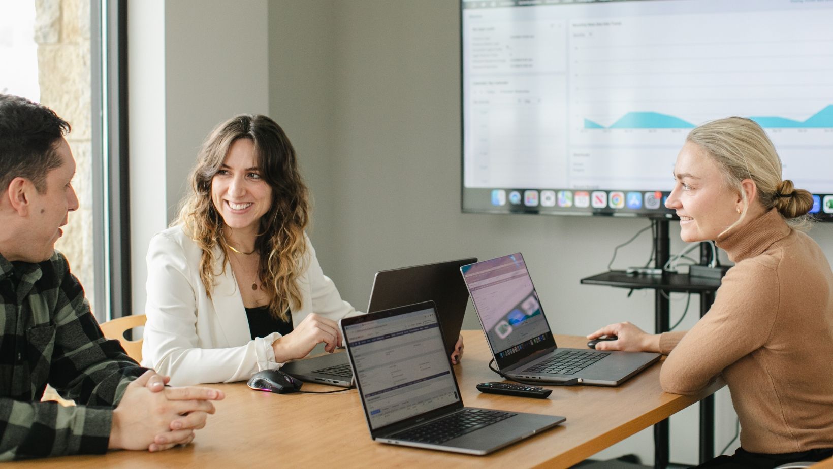 A group of people are sitting at a table with laptops.