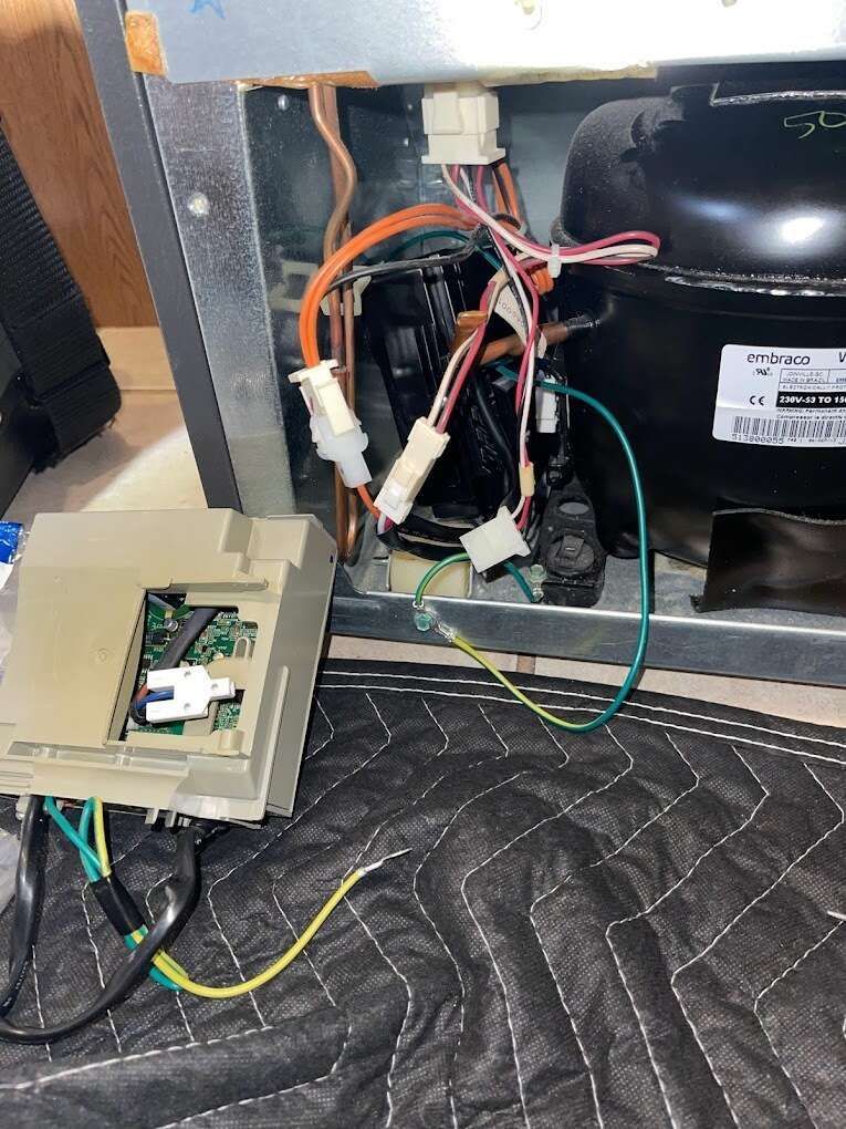 the inside of a refrigerator with a lot of wires coming out of it .