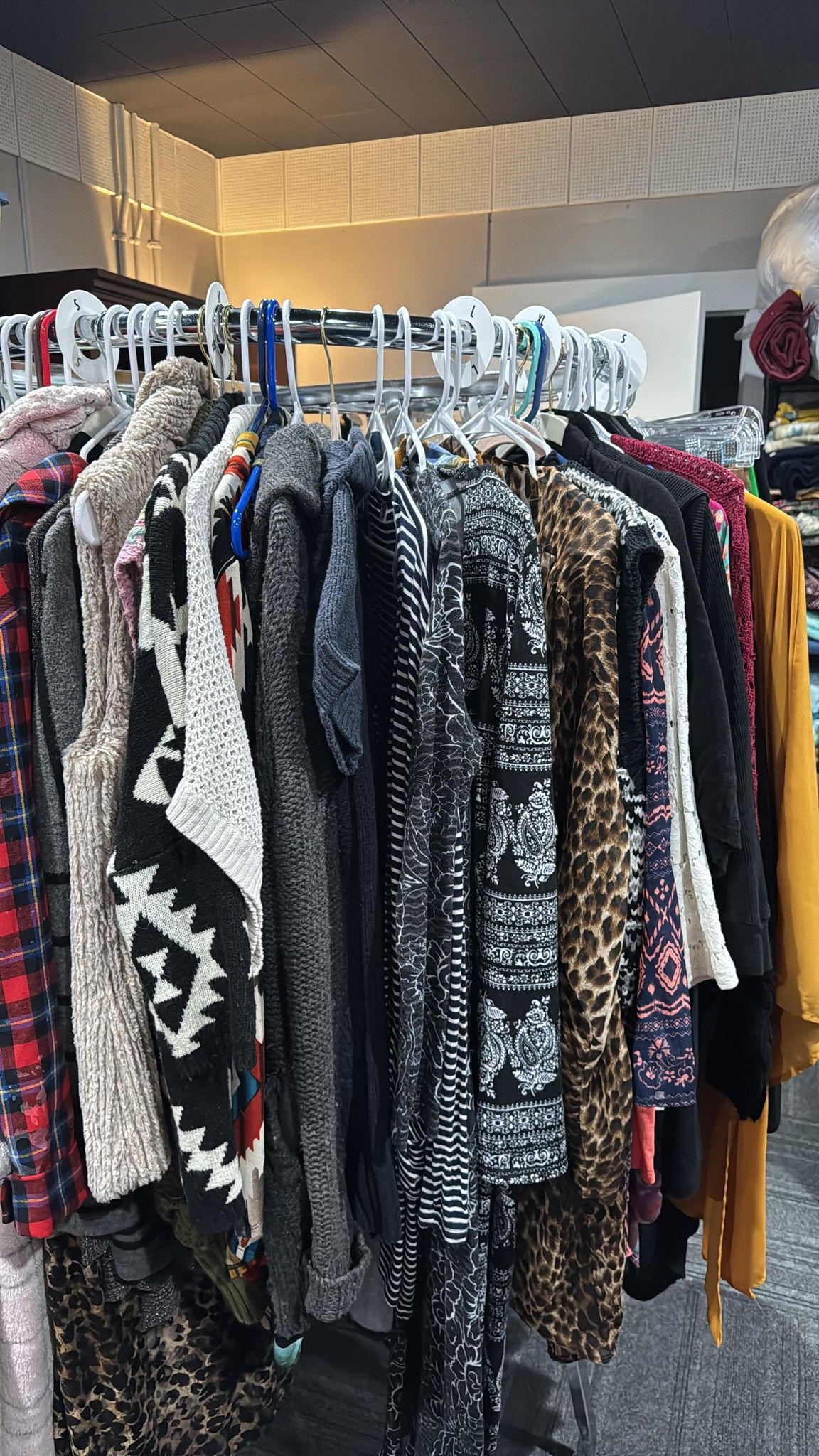 Racks of colorful patterned sweaters and clothing in a store display