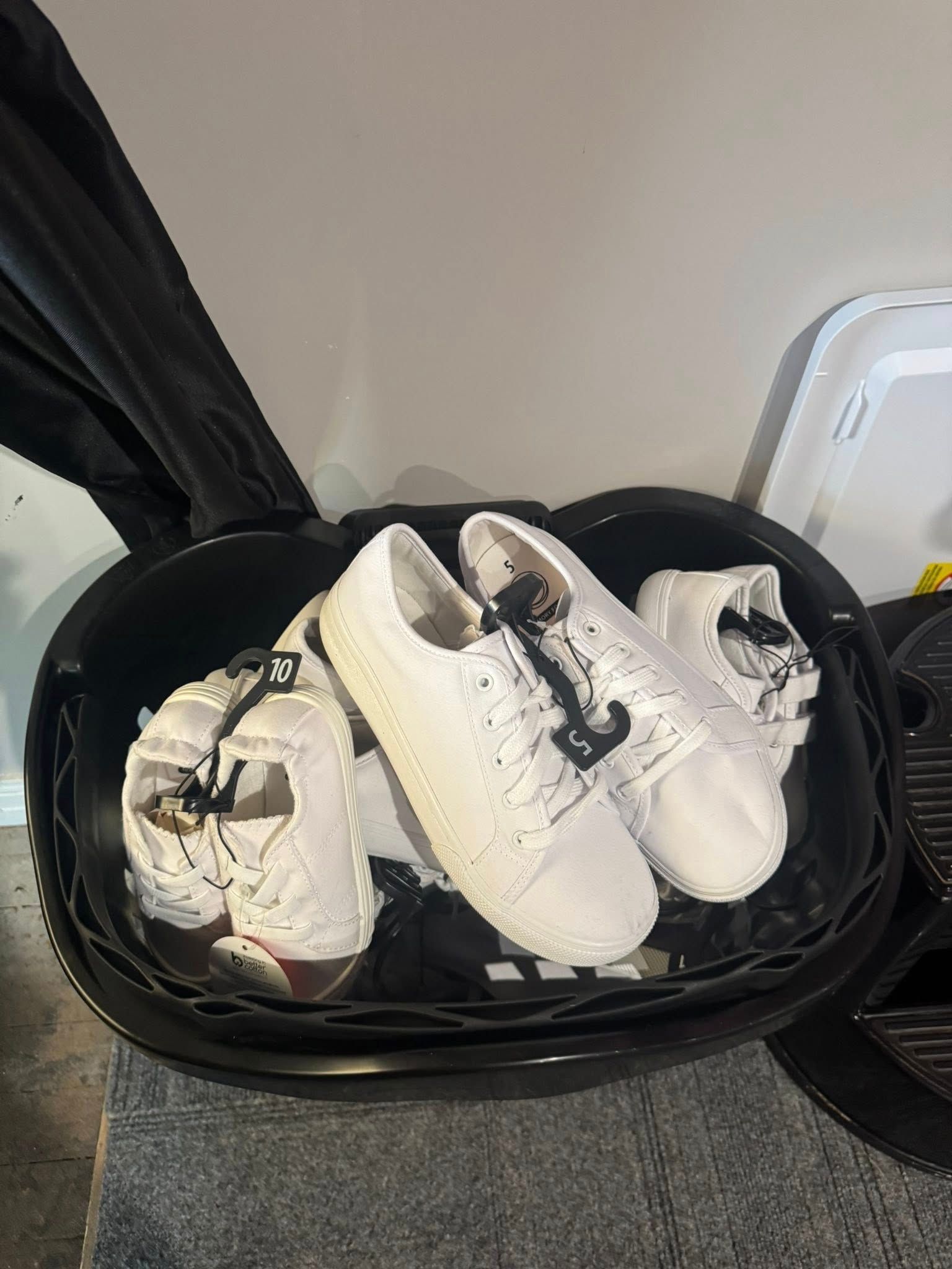 Open suitcase holding a pair of white sneakers on a carpeted floor