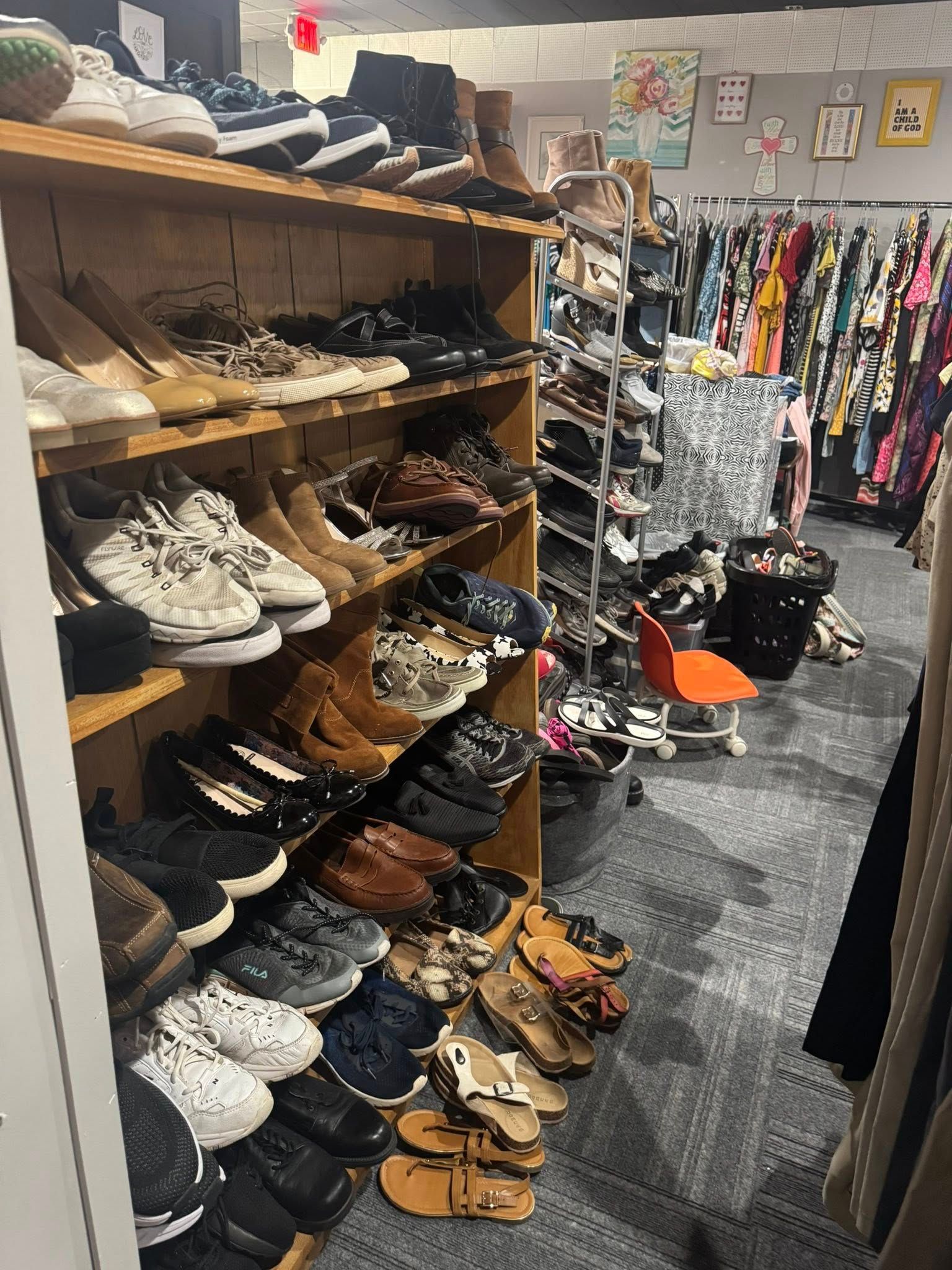 A shoe store aisle with wooden shelves packed with sneakers, sandals, and casual shoes.