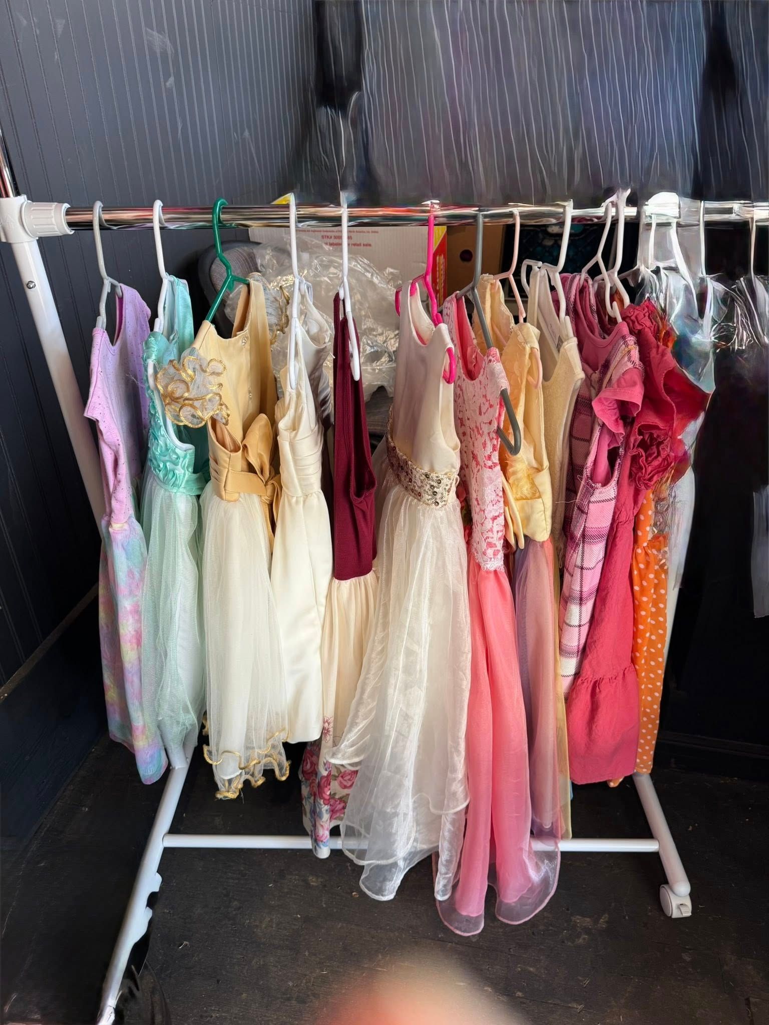 Rack of assorted pastel dresses and gowns hanging on hangers indoors