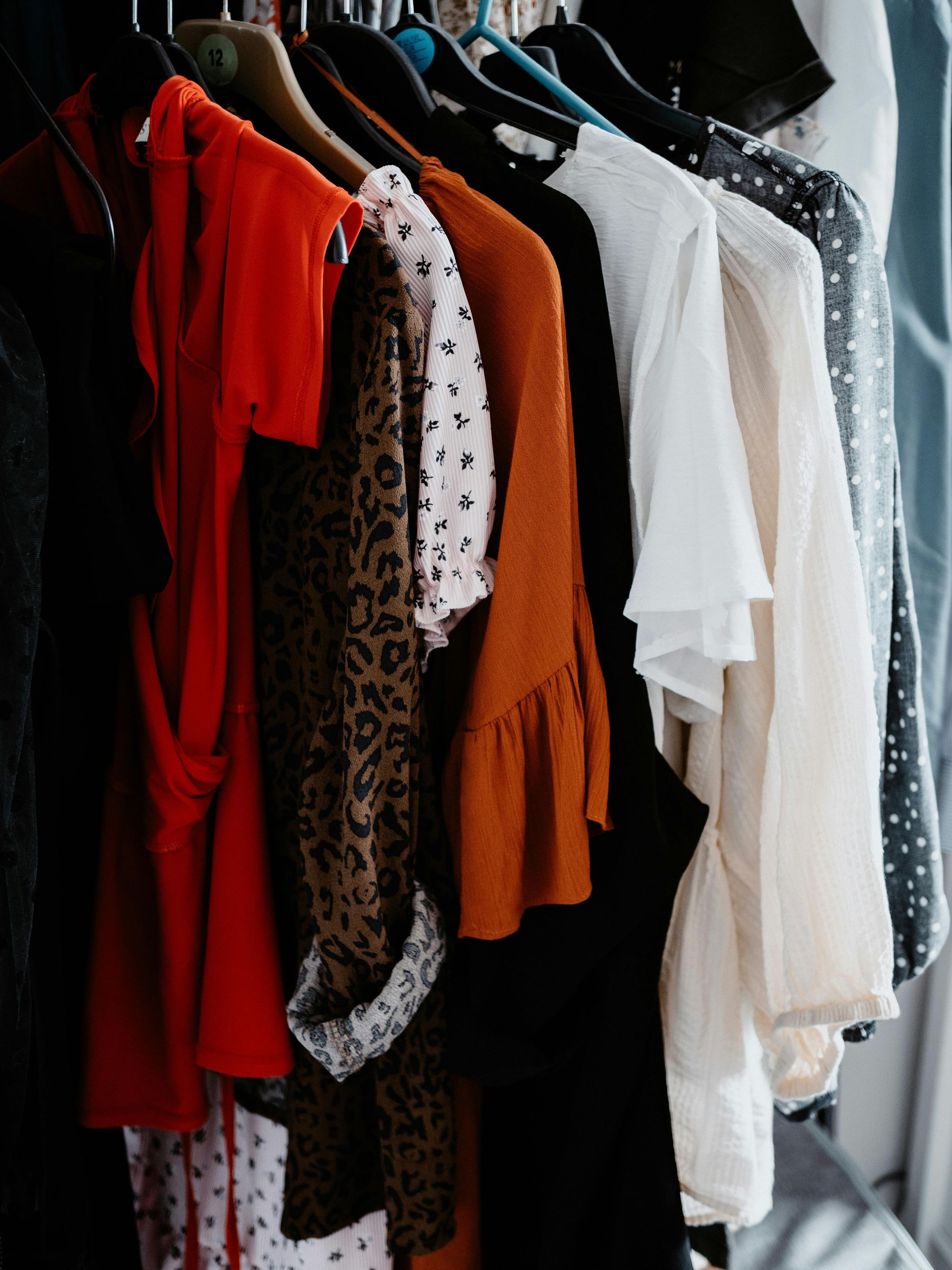 Clothing rack with assorted hanging garments in red, orange, white, and black patterns