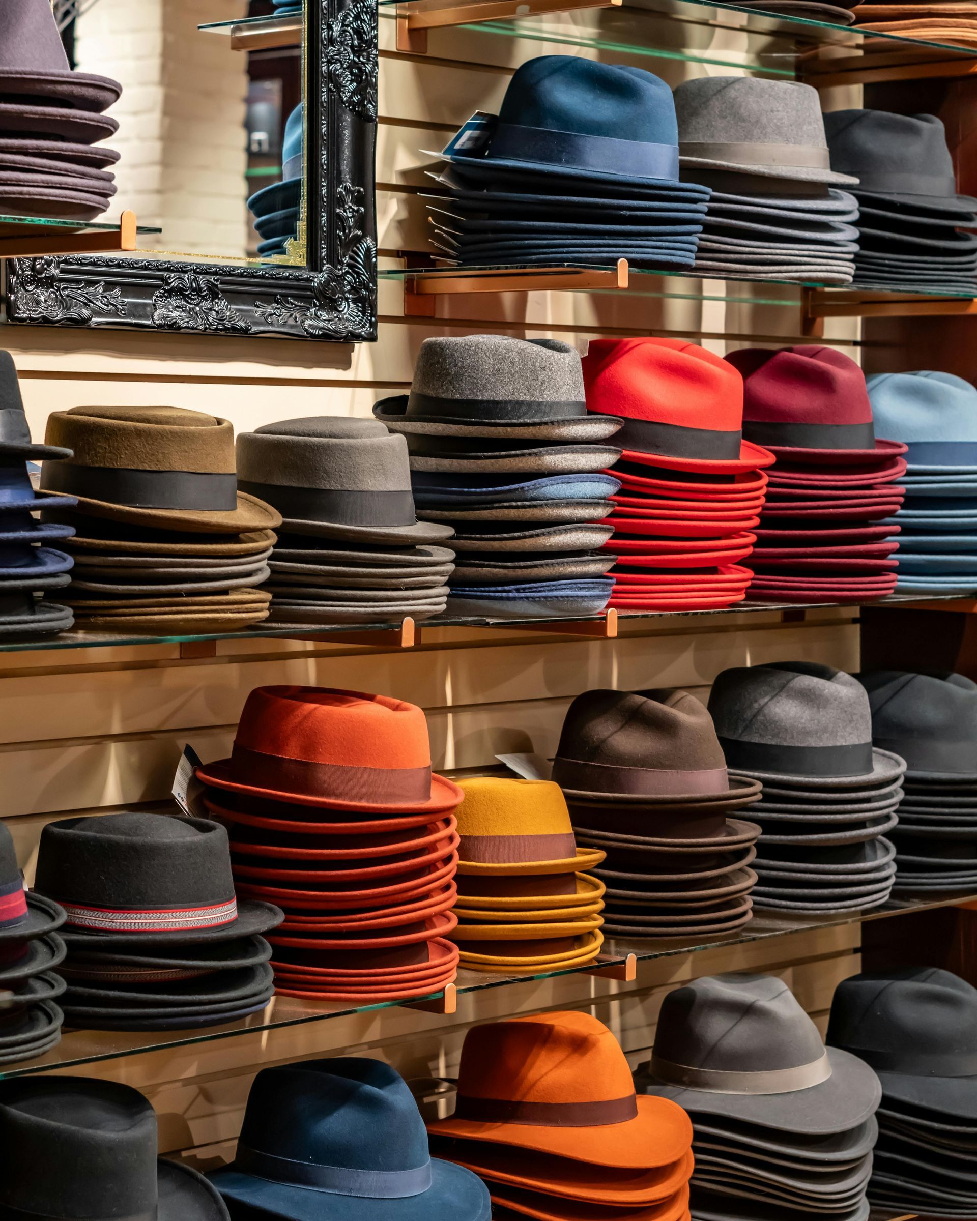 Shelves stacked with folded hats in many colors, neatly arranged in a retail store.