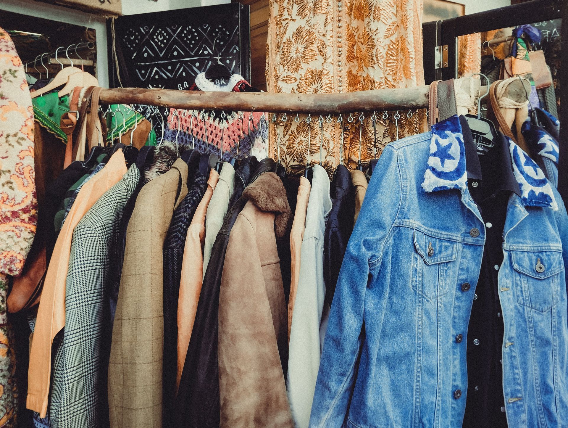 Clothes rack with hanging coats and denim vests in a small shop or closet