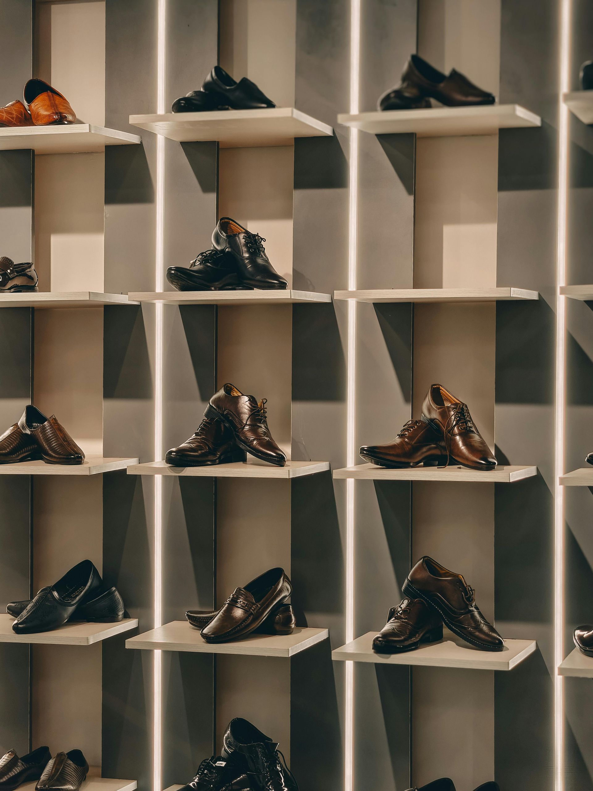 Shoes displayed on beige wall shelves in a retail store