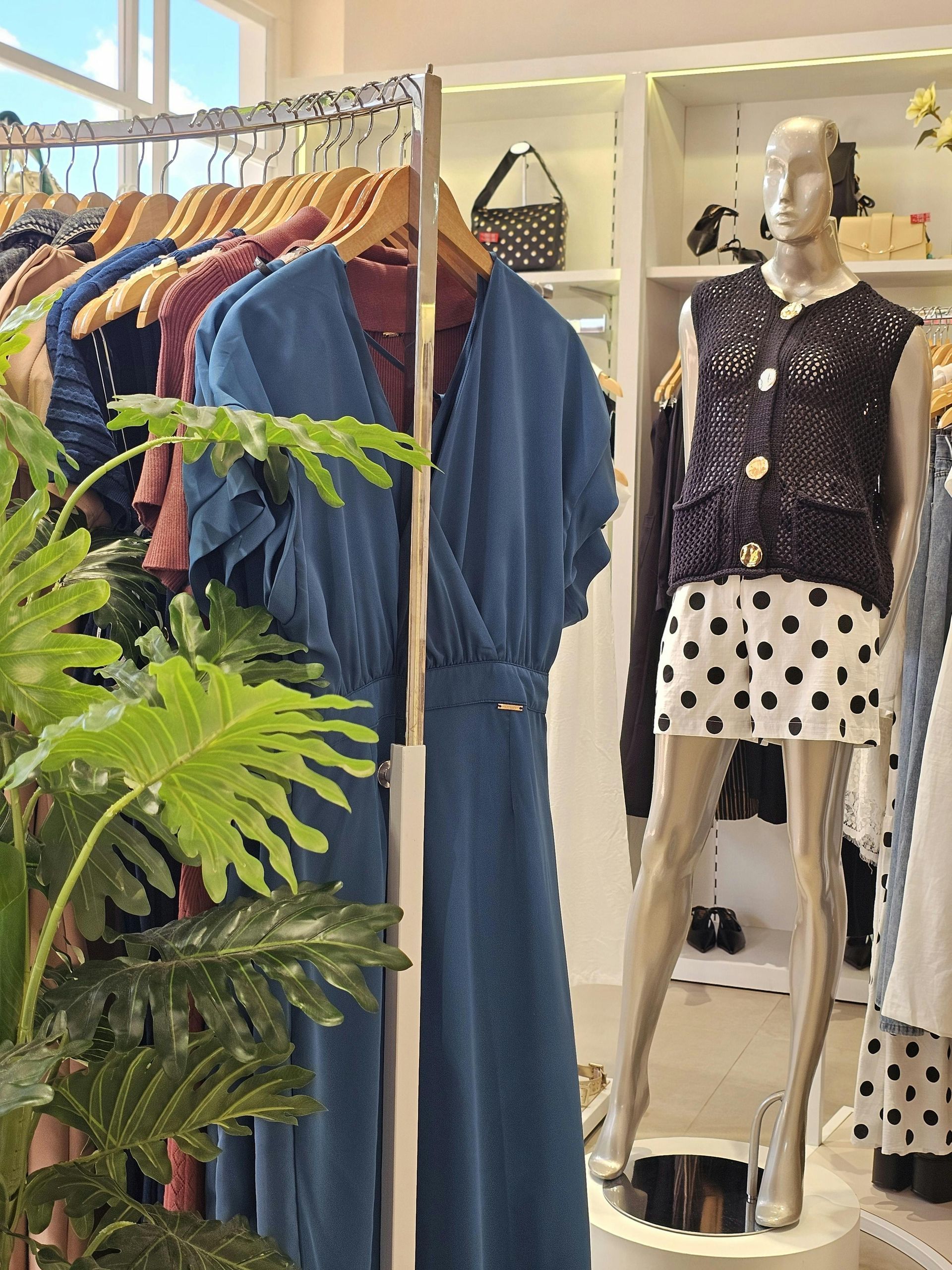 Clothing boutique display with hanging garments and a mannequin wearing a black top and polka dot skirt and pants