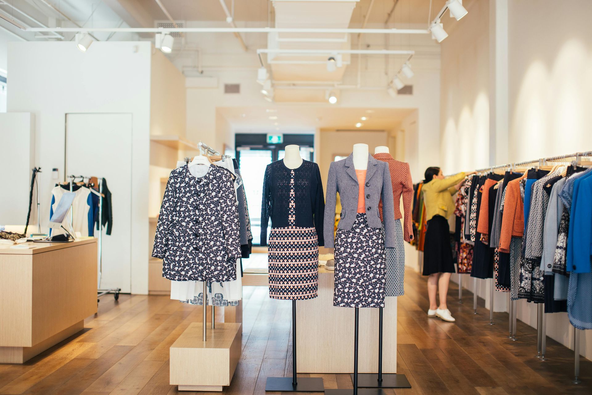 Clothing boutique interior with racks of patterned dresses and tops under bright ceiling lights