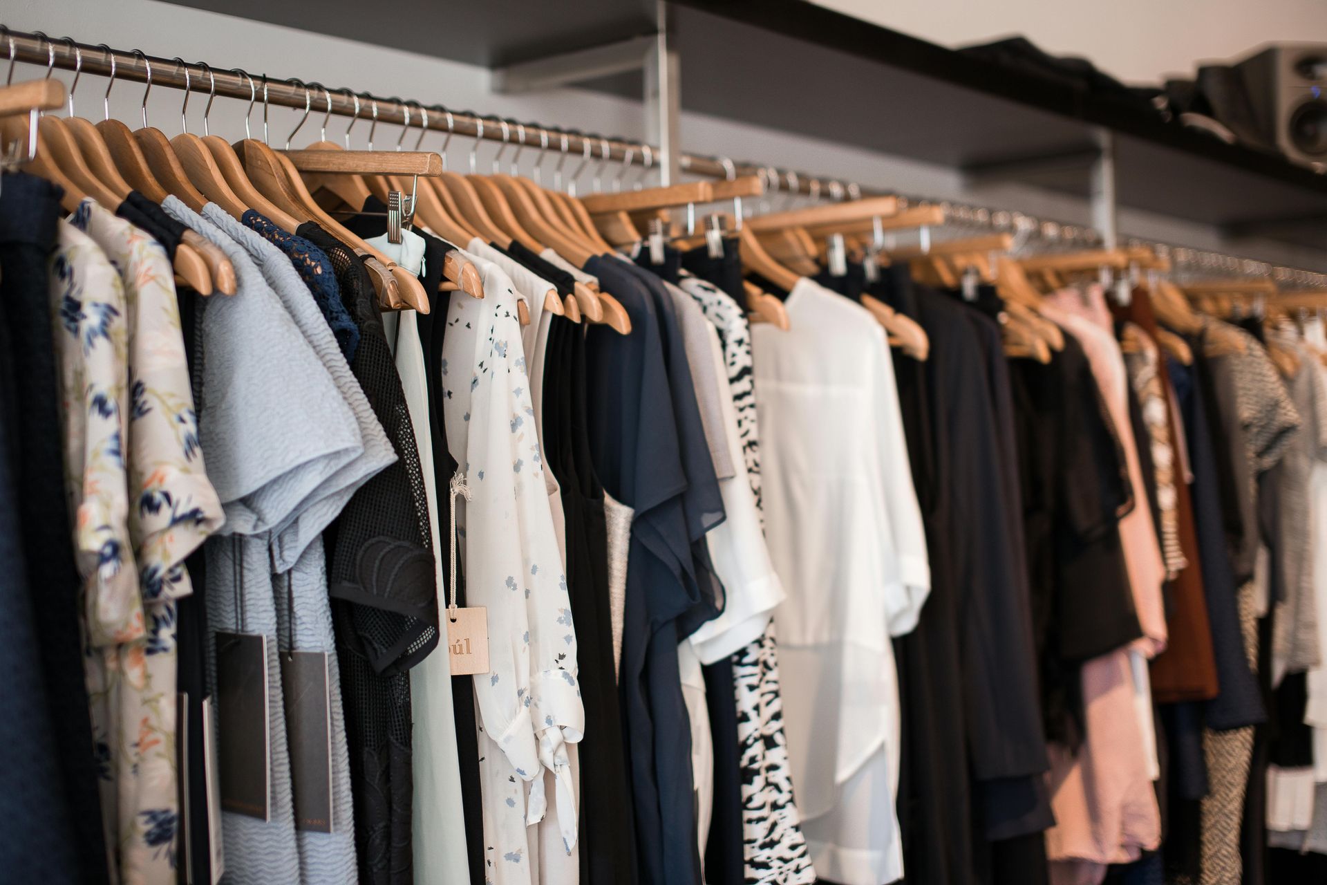 Clothing rack with assorted shirts and jackets on wooden hangers in a shop