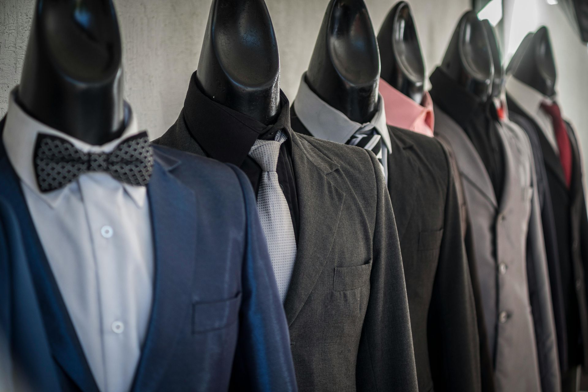 Row of mannequins dressed in formal suits and bow ties in a shop display