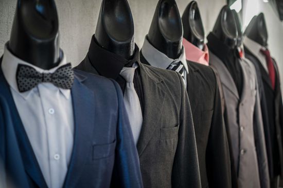 Row of mannequins dressed in formal suits and bow ties in a shop display