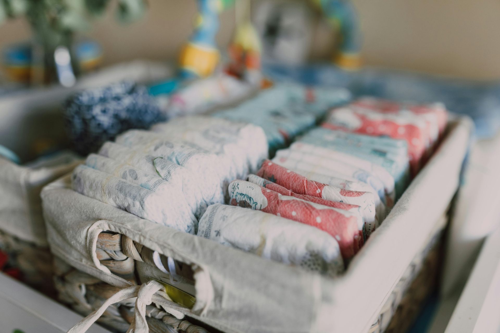 Open basket filled with neatly folded diapers and baby wipes on a table
