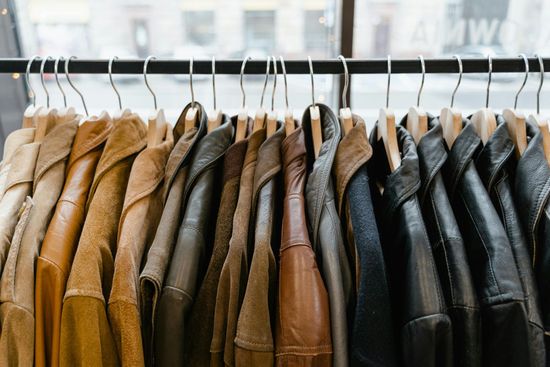 Row of brown and black leather jackets hanging on a clothing rack