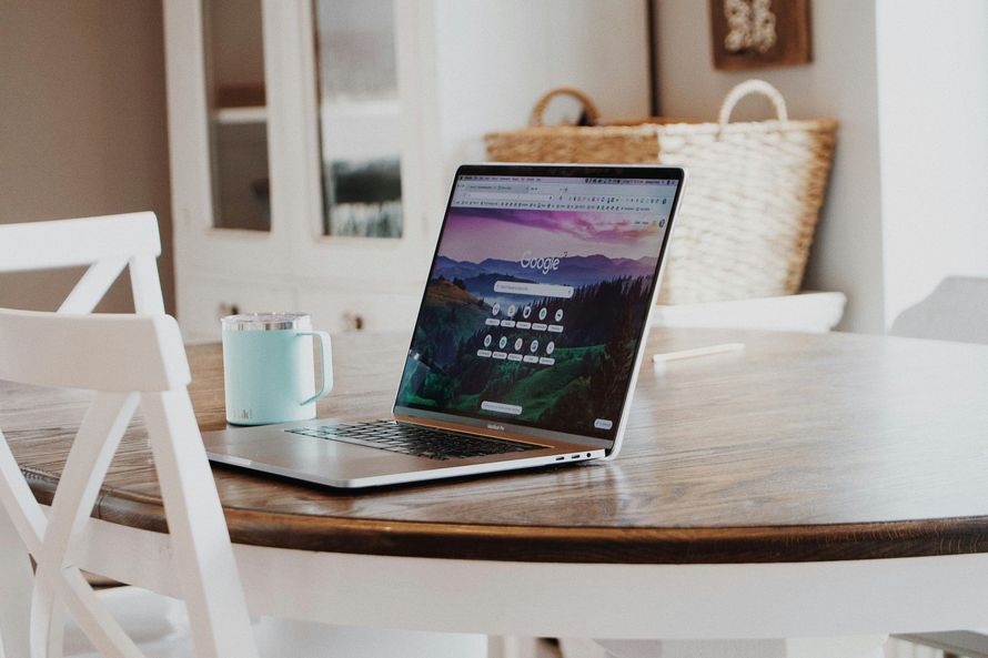 A laptop is sitting on a wooden table next to a cup of coffee.