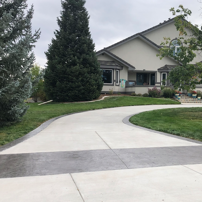 A concrete driveway leading to a large house